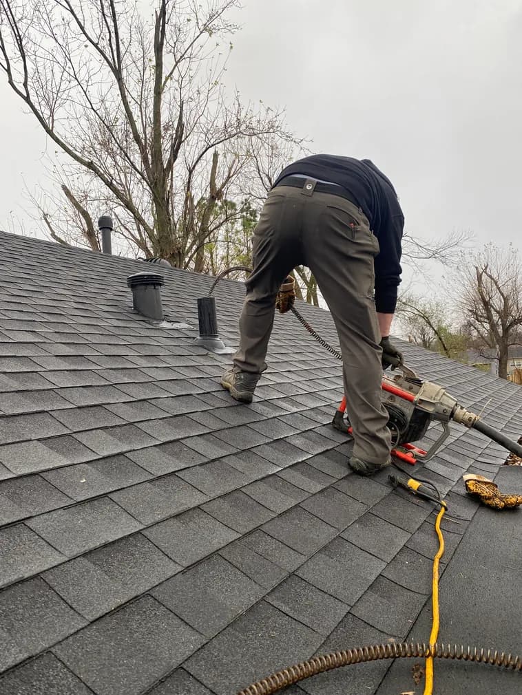 All Calls Plumbing technician clearing a drain line on a rooftop vent